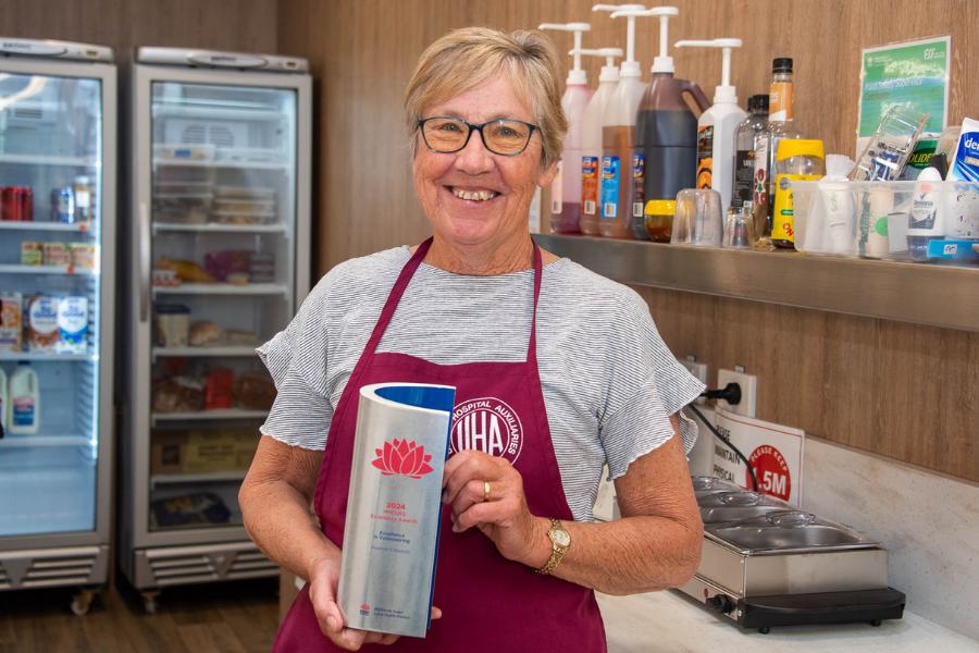 A woman standing in a commercial kitchen holding a trophy.